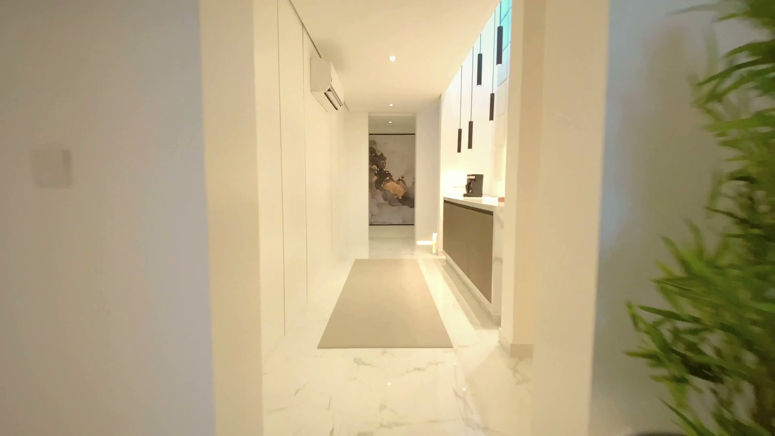 Warm-toned modern luxury interior hallway with wood cabinetry, marble flooring, and architectural glass